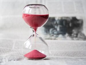 hourglass with red sand sitting on newspaper