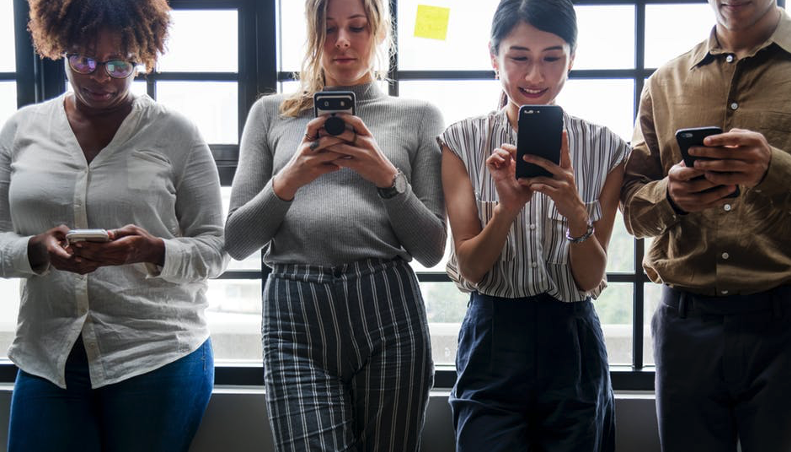 group of women standing together, all on their phones