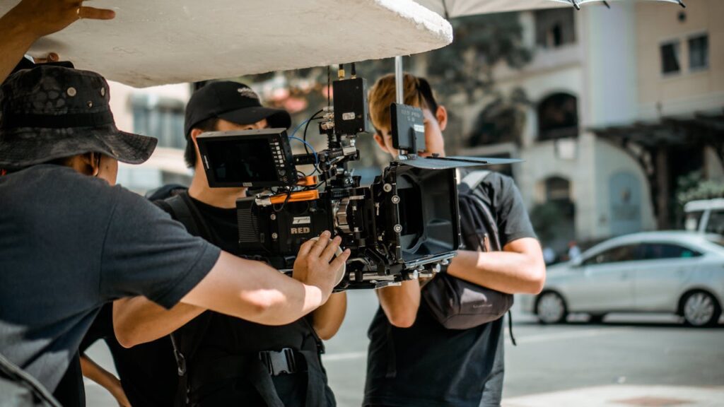 Three people operate a camera outside on a sidewalk