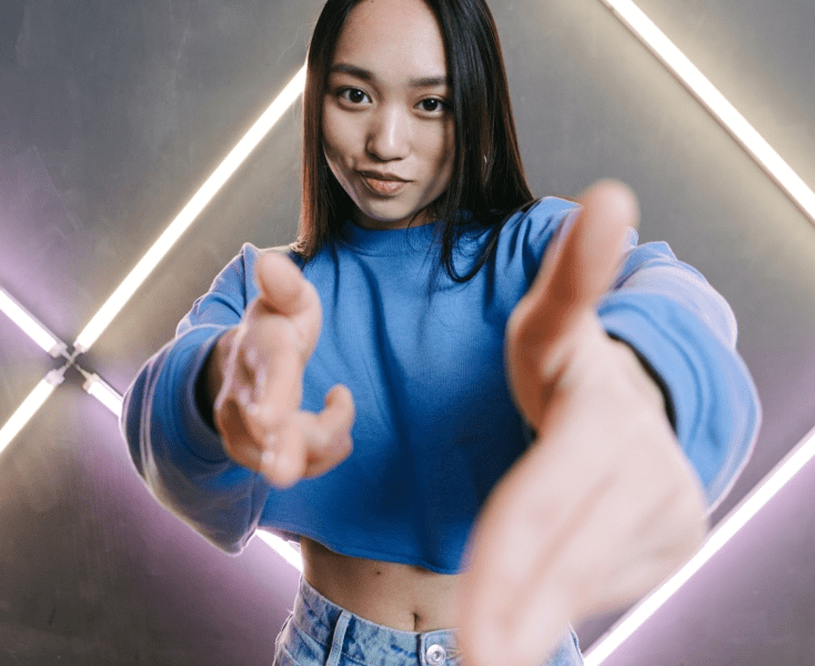 A young girl in a blue shirt pointing finger guns at the camera