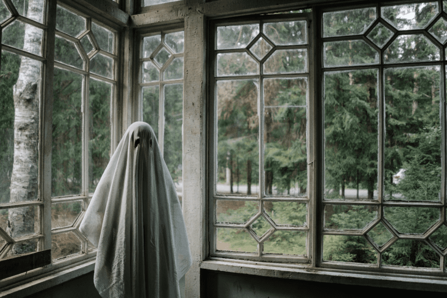 A person disguised as a ghost using a white sheet