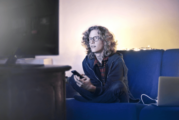 a man wearing glasses watching a movie on his TV