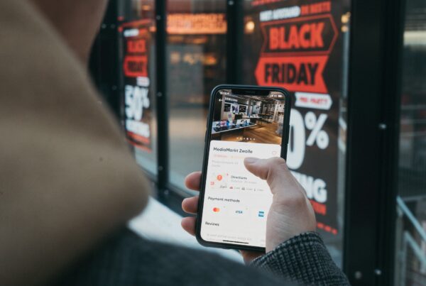 Person watching a video on a smartphone beside a Black Friday sign