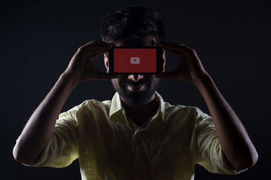 Man holding up a smartphone with the YouTube logo